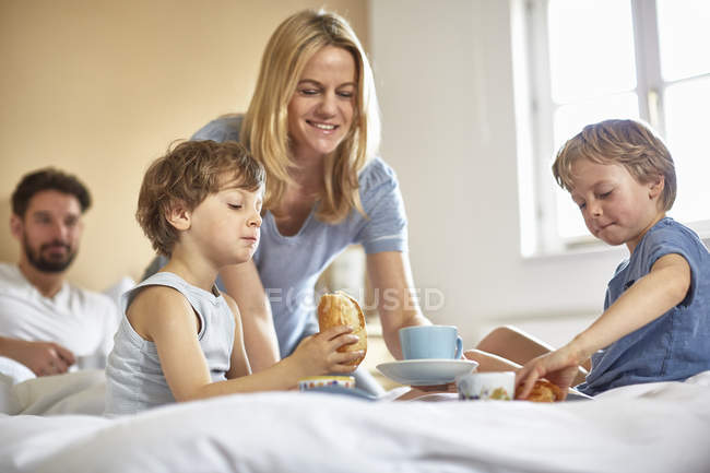 Garçons prenant le petit déjeuner dans le lit des parents — Photo de stock