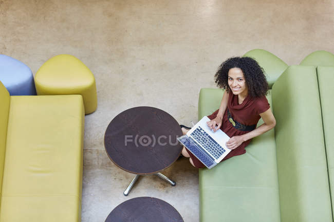 Overhead portrait of businesswoman using laptop on design studio sofa — Stock Photo