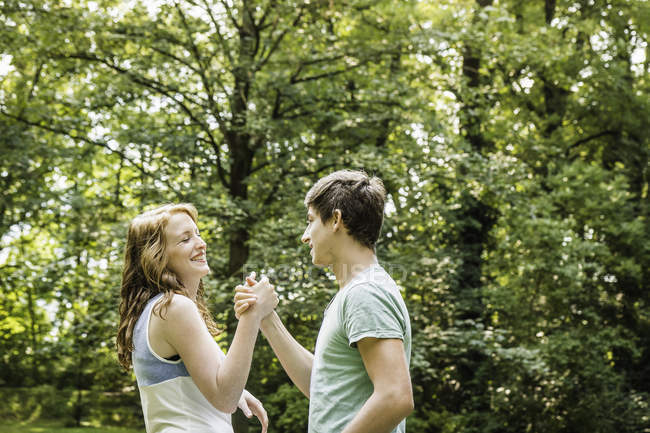 Jeune couple tenant la main dans le parc — Photo de stock