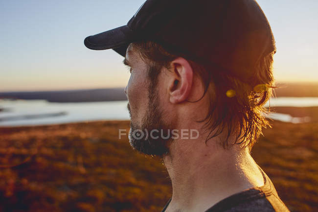 Чоловік дивиться озеро на вершині скелі на заході сонця, Keimiotunturi, тихий, Фінляндія — стокове фото