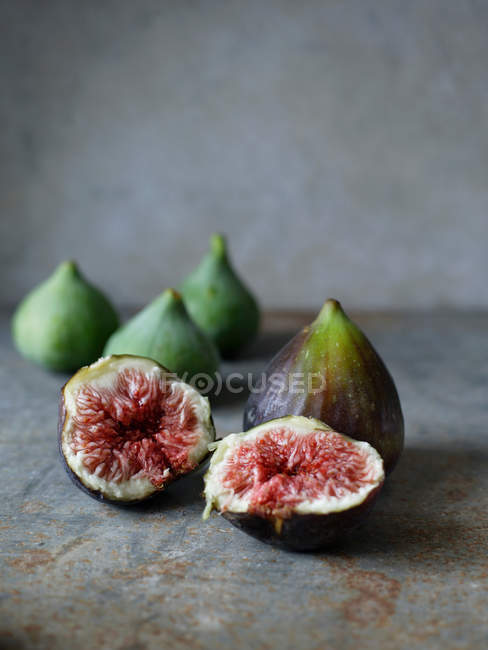 Fresh figs and halves on concrete surface — Stock Photo