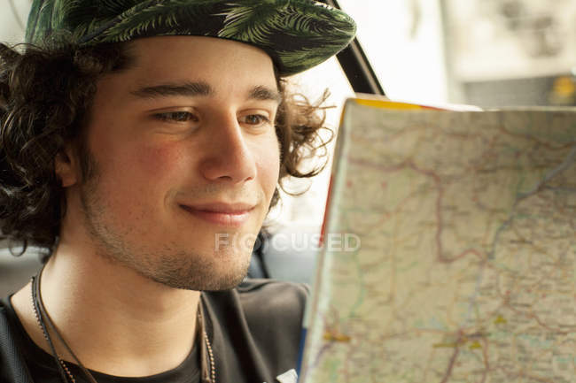 Young man reading map in back seat of taxicab, Rio De Janeiro, Brazil — Stock Photo