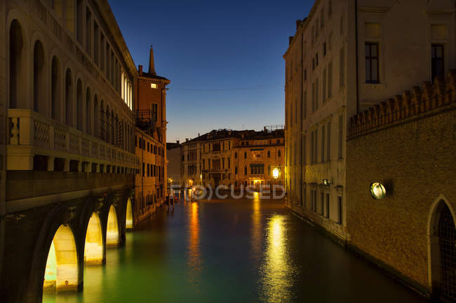 Edifícios com luzes refletidas na água do canal urbano — Fotografia de Stock