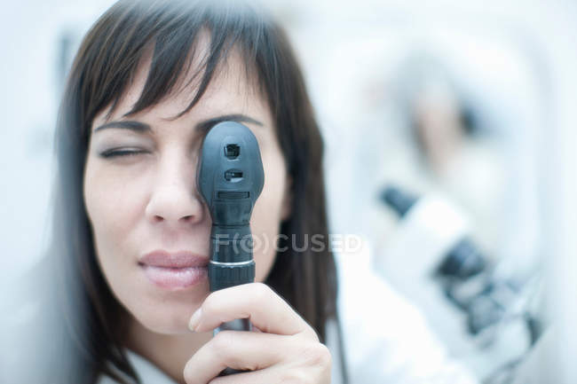 Óptico mirando a través del oftalmoscopio - foto de stock