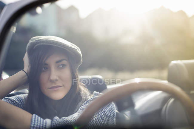 Junge Frau mit Schiebermütze im Cabrio — Stockfoto