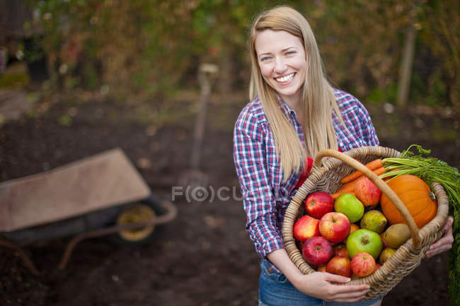 Woman gathering vegetables in garden — Stock Photo