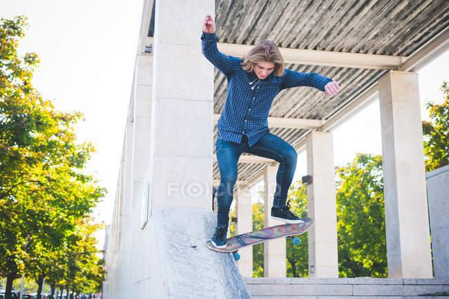 Молодой городской скейтбордист спускается по бетонной конструкции — стоковое фото