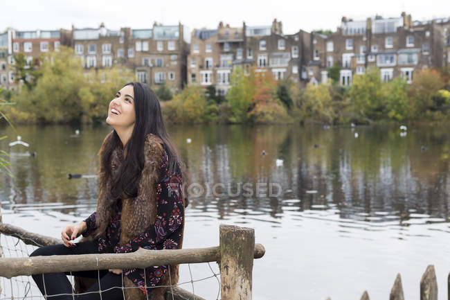 Mujer joven relajándose junto al lago, Hampstead Heath, Londres - foto de stock