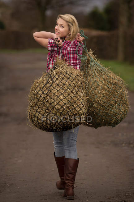 Дівчинка-підліток, несучи сіно бруду шлях — стокове фото