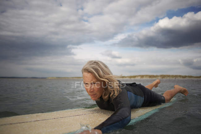 Seniorin auf Surfbrett im Meer, Paddelboot — Stockfoto