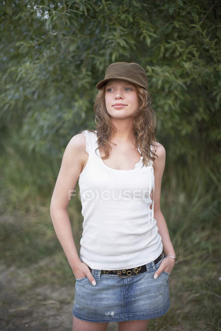 Portrait of young woman wearing cap with hands in pockets — Stock Photo