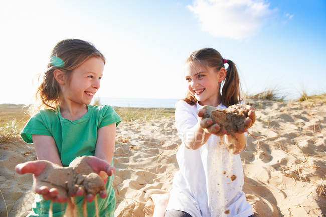 Two girls playing with sand on beach — Stock Photo