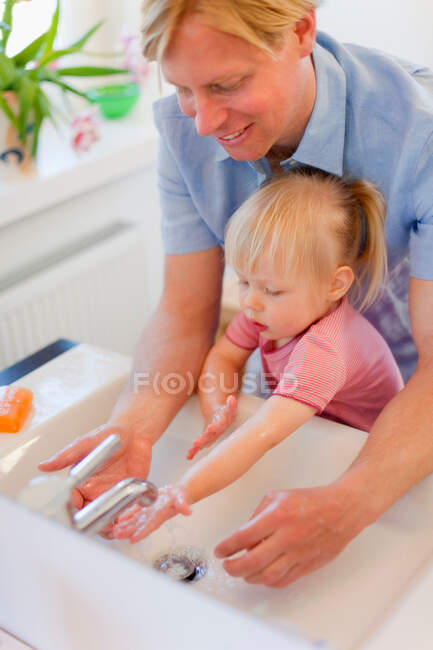 Padre e hija lavándose las manos - foto de stock