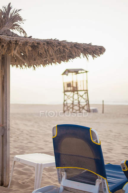 Lawn chair and umbrella on beach — Stock Photo