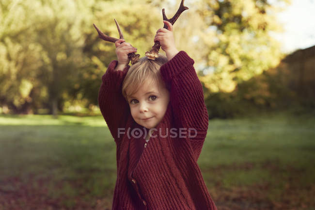 Niño pequeño usando palos como astas - foto de stock