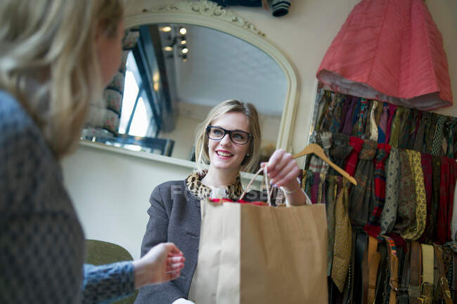 Verkäuferin übergibt Einkaufstasche an Dame — Stockfoto