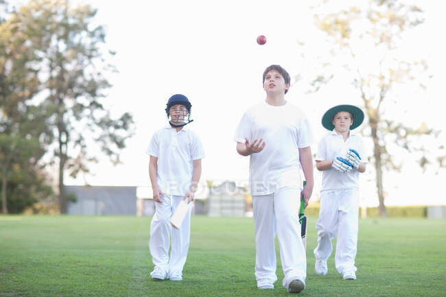 Três meninos andando no campo de críquete — Fotografia de Stock