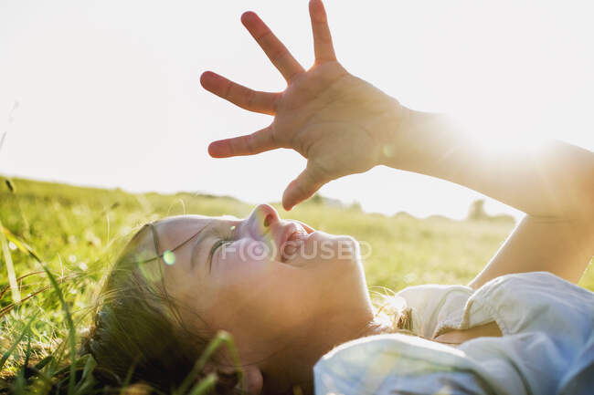 Mädchen liegt im Park und schirmt Augen vor Sonnenlicht ab — Stockfoto