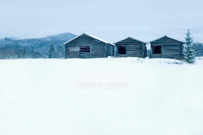Holzhäuser im verschneiten Feld — Stockfoto
