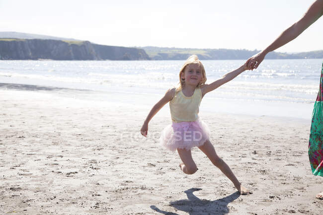 Mãe e filha usando tutu correndo na praia, País de Gales, Reino Unido — Fotografia de Stock