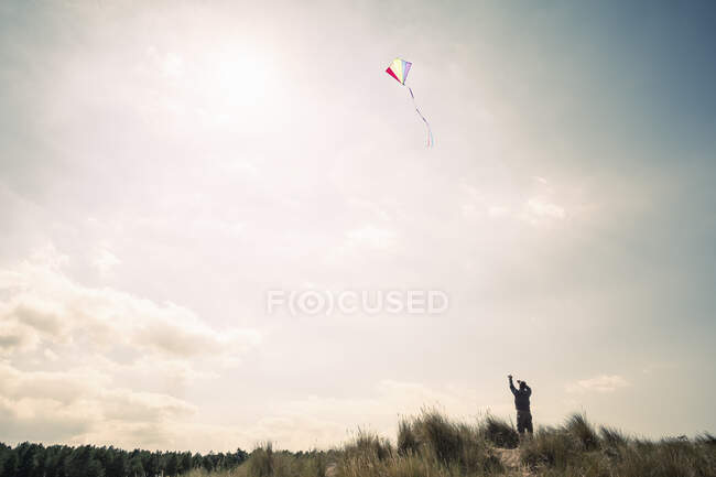 Homem silhueta voando uma pipa na costa de Norfolk, Reino Unido — Fotografia de Stock