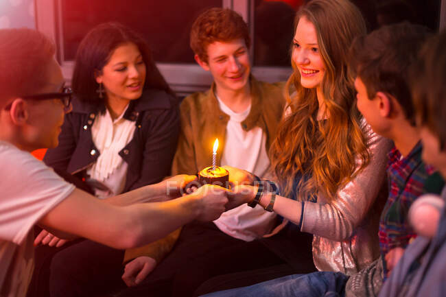 Grupo de adolescentes sentados em torno de bolo de aniversário — Fotografia de Stock