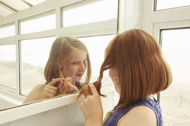 Girl plaiting hair in holiday apartment porch — Stock Photo