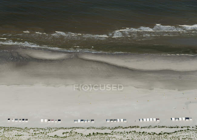 Вид с воздуха на пляж с пляжными каютами и волнами для серфинга — стоковое фото