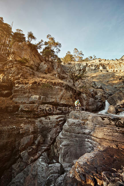 Man mountain biking on rocks by cliffs — Stock Photo