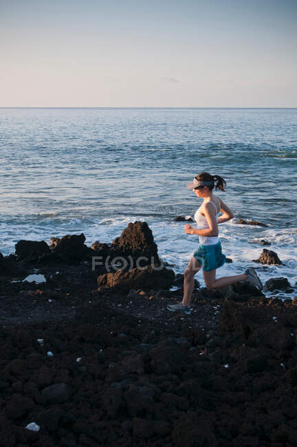 Donna che corre sulla spiaggia rocciosa — Foto stock