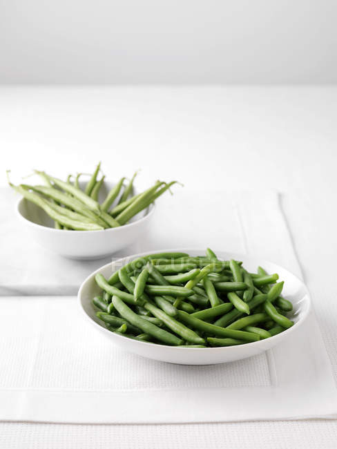Feijão verde cru na tábua de corte e tigela de feijão verde cozido — Fotografia de Stock