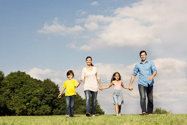 Сім'я з двома дітьми тримає руки, ходить — стокове фото