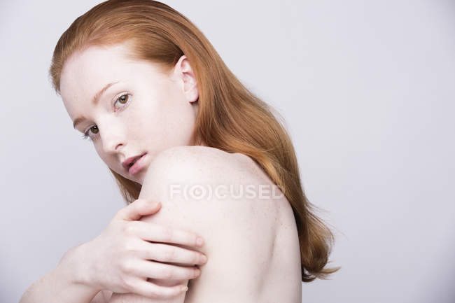 Retrato de mujer joven, vista lateral, hombros desnudos, mirando a la cámara - foto de stock