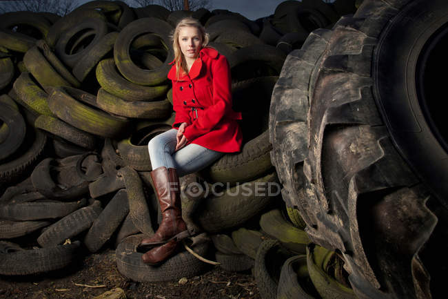 Adolescente sentada em pneus descartados — Fotografia de Stock