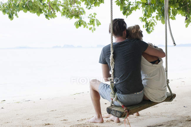 Visão traseira do jovem casal sentado no balanço da praia, Kradan, Tailândia — Fotografia de Stock