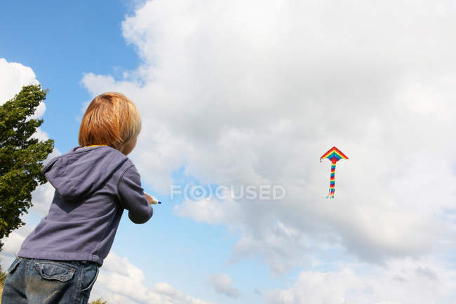 Junge fliegenden Drachen im Freien, niedrigen Winkel Blick — Stockfoto