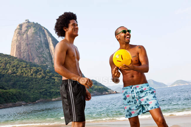 Dos amigos en la playa con voleibol, Río de Janeiro, Brasil - foto de stock