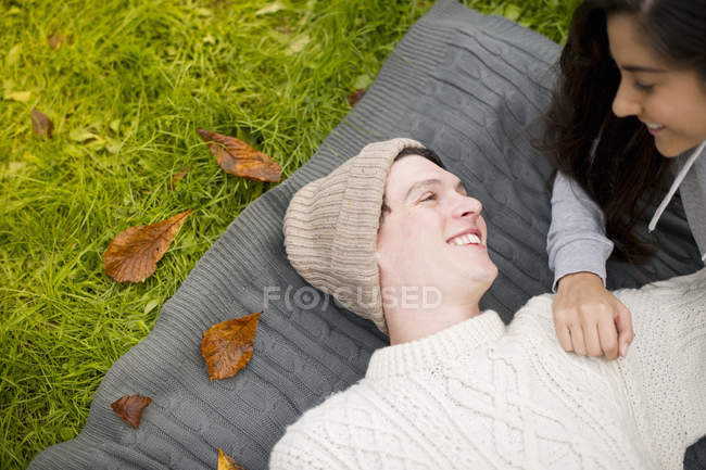 Giovane coppia sdraiato sul tappeto, l'uomo indossa cappello di maglia — Foto stock