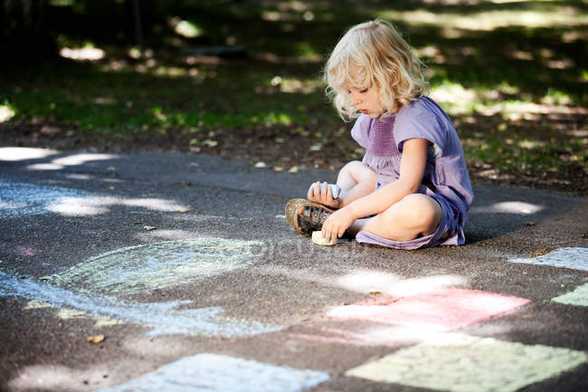 Девушка рисует мелом на тротуаре — стоковое фото