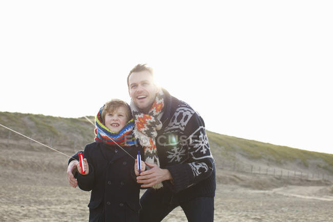 Взрослый человек, летящий змеем с сыном на пляже, Блумендал-ан-Зи, Нидерланды — стоковое фото