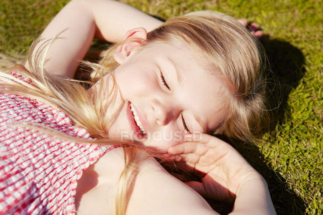 Child lying down on grass — Stock Photo