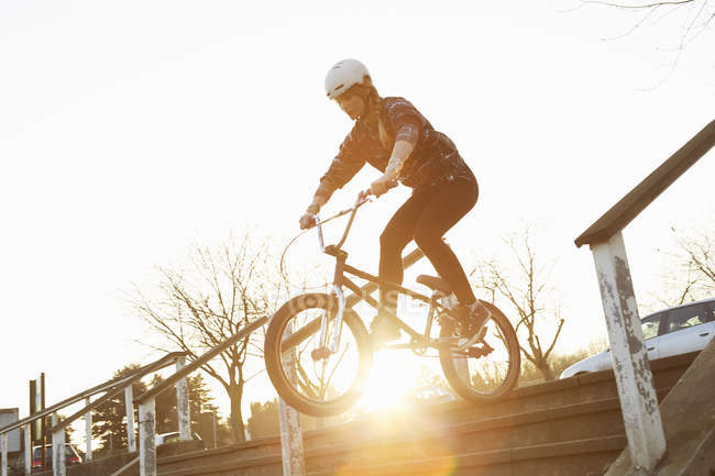 BMX-Fahrerin reitet sonnenbeschienene Treppe hinunter — Stockfoto
