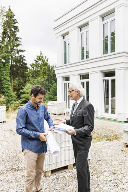 Builder and architect on construction site discussing plans smiling — Stock Photo