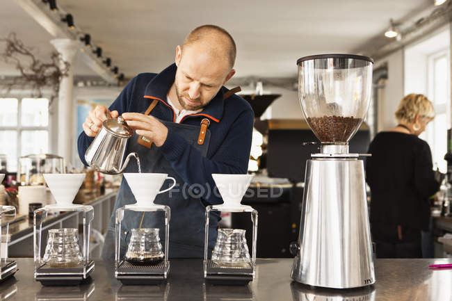 Barista versando acqua bollente nei filtri del caffè — Foto stock