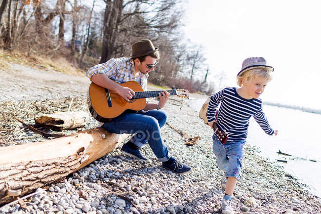 Father and son with guitars by creek — Stock Photo