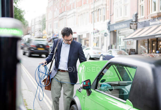 Homme recharge voiture électrique dans la rue — Photo de stock