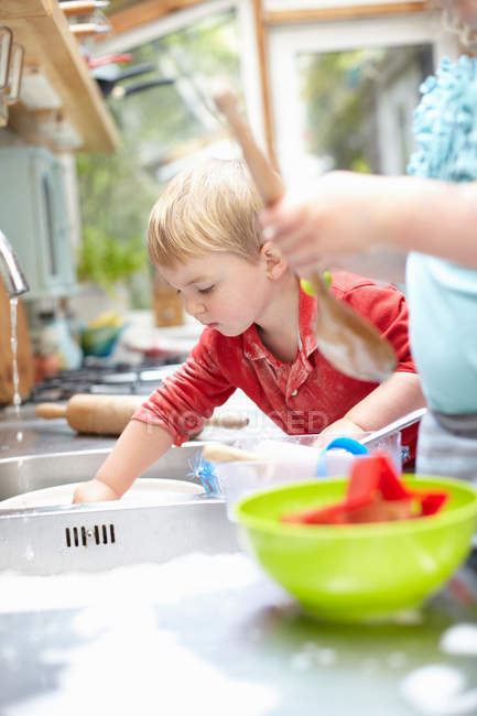 Niños lavando platos juntos - foto de stock