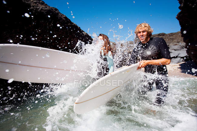 Couple running in water with surfboards — Stock Photo