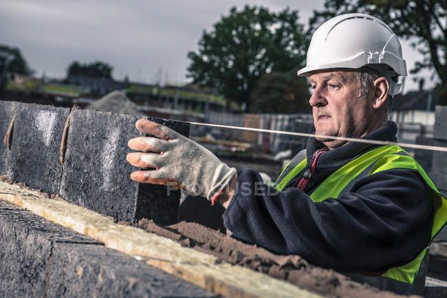 Trabalhadores que colocam tijolos no estaleiro de construção — Fotografia de Stock