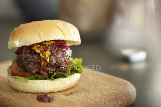 Homemade burger on wooden cutting board — Stock Photo